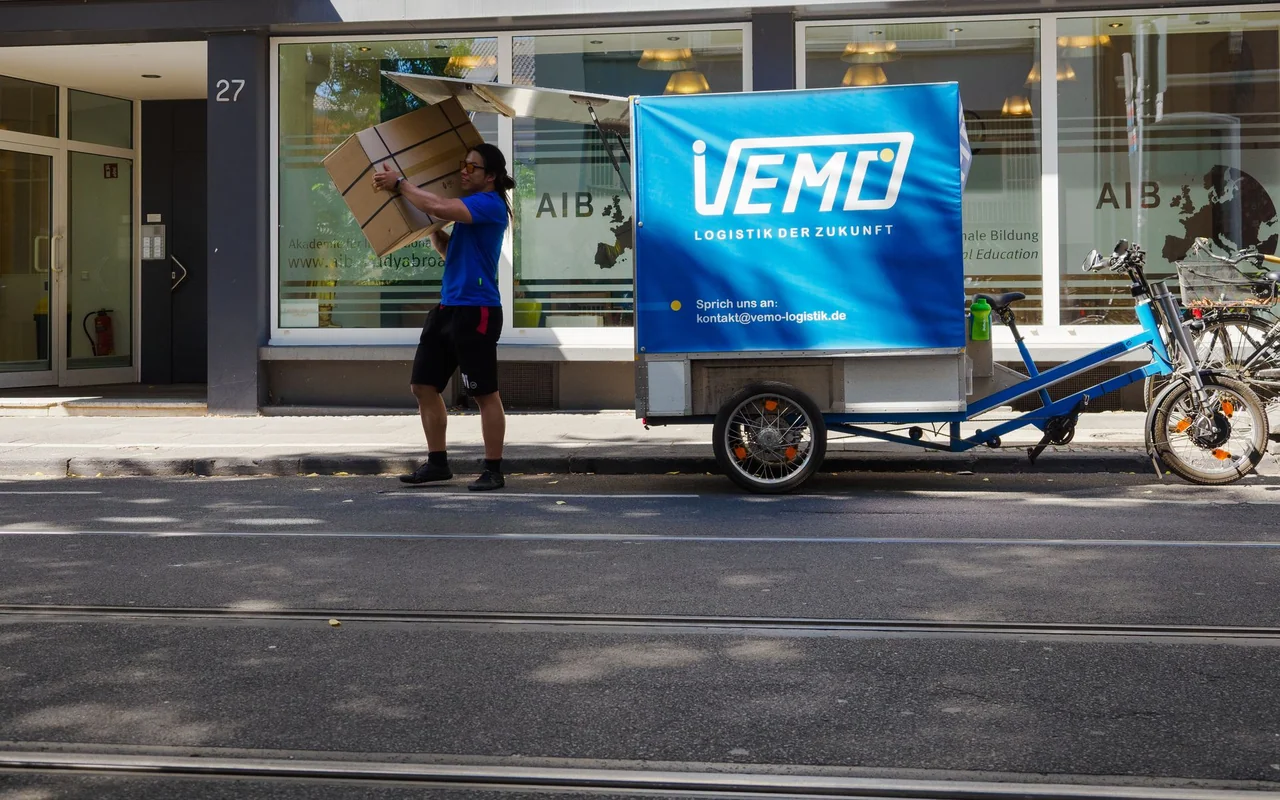 VEMO-Fahrer lädt einen Karton in den Kasten eines Lastenrads in Bonn